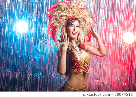 Cabaret, dancer and holidays concept - Cute young girl in bright colorful carnival costume on dark 58074516