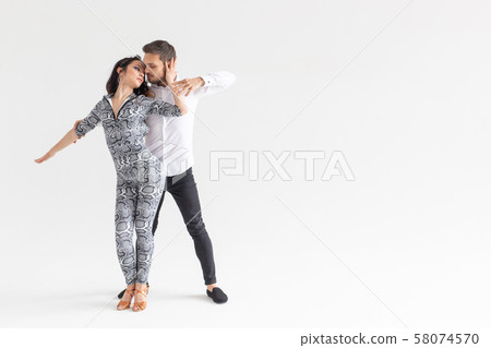 Social dance, kizomba, tango, salsa, people concept - beautiful couple dancing bachata on white Social dance, kizomba, tango, salsa, people concept - beautiful couple dancing bachata on white 58074570