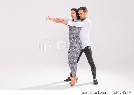 Social dance, bachata, kizomba, tango, salsa, people concept - Young couple dancing over white Social dance, bachata, kizomba, tango, salsa, people concept - Young couple dancing over white 58074599