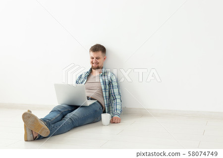 Positive young man in casual clothes and glasses surfing the Internet using Wi-Fi and a laptop in Positive young man in casual clothes and glasses surfing the Internet using Wi-Fi and a laptop in 58074749