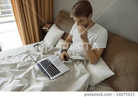 Man working remotely inspite of having cold Man working remotely inspite of having cold 58075815