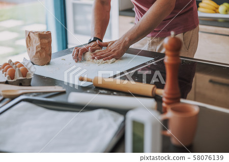 Cook working with dough in his kitchen 58076139