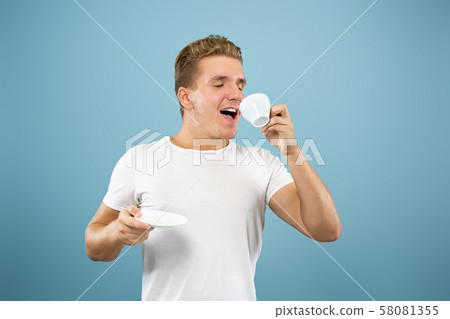 Caucasian young man's half-length portrait on blue background Caucasian young man's half-length portrait on blue background 58081355