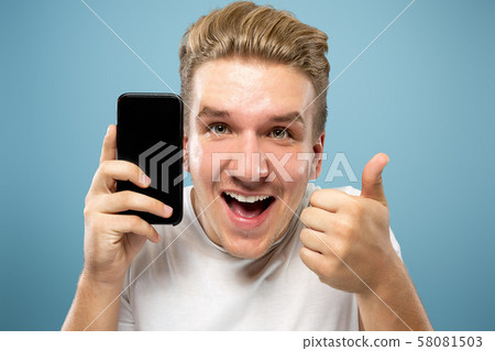 Caucasian young man's half-length portrait on blue background Caucasian young man's half-length portrait on blue background 58081503