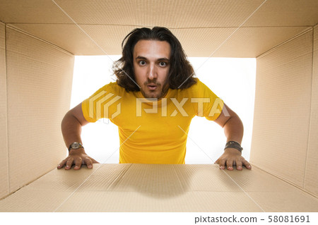 Young man opening the biggest postal package isolated on white Young man opening the biggest postal package isolated on white 58081691