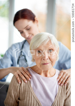 Caregiver doing massage for retired aged woman 58081734