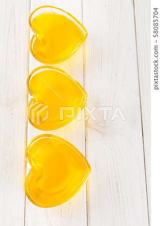 Yellow lemon jelly in heart shaped glass on white Yellow lemon jelly in heart shaped glass on white 58085704