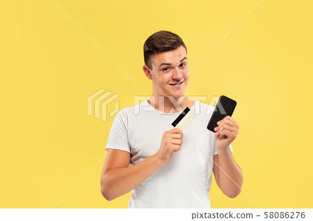 Caucasian young man's half-length portrait on yellow background 58086276