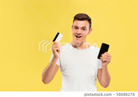 Caucasian young man's half-length portrait on yellow background 58086278