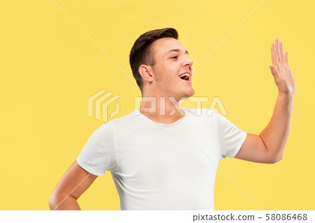 Caucasian young man's half-length portrait on yellow background 58086468