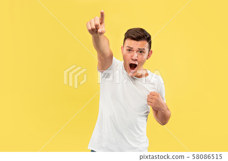 Caucasian young man's half-length portrait on yellow background 58086515