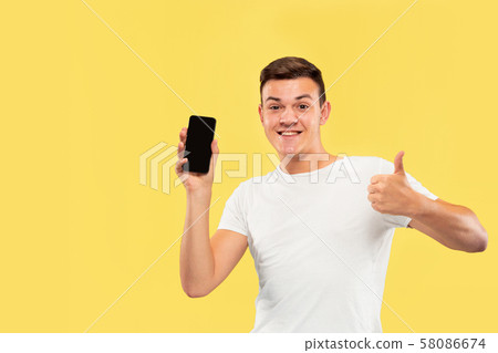 Caucasian young man's half-length portrait on yellow background 58086674