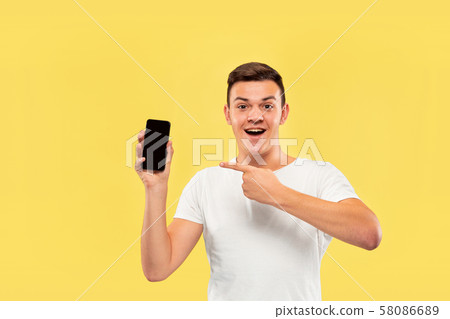 Caucasian young man's half-length portrait on yellow background Caucasian young man's half-length portrait on yellow background 58086689