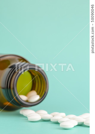 White round tablets scattered near glass bottle of White round tablets scattered near glass bottle of 58090046