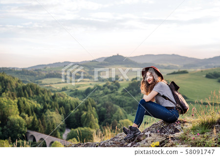 Young tourist woman traveller with backpack sitting in nature. Young tourist woman traveller with backpack sitting in nature. 58091747