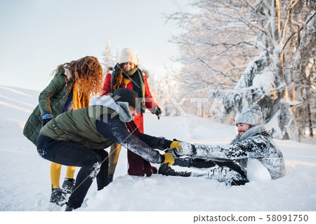 A group of young friends on a walk outdoors in snow in winter forest. 58091750