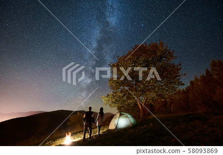 Couple tourists resting at night camping under stars Couple tourists resting at night camping under stars 58093869