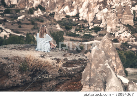 Girl sitting on the top of mountain in Cappadocia, Turkey. Aerial view on the famous stone peaks 58094367