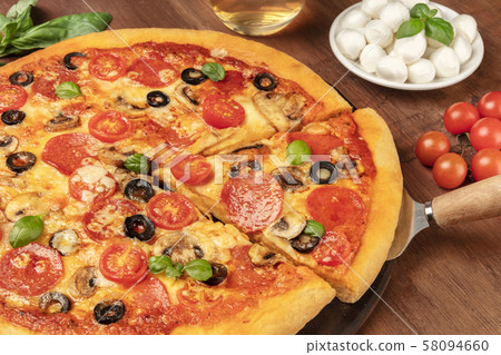 Pepperoni pizza with salami slices, black olives, mushrooms, fresh basil leaves and a lot of cheese 58094660