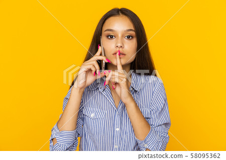 Woman talking phone and showing to keep silence sign. 58095362