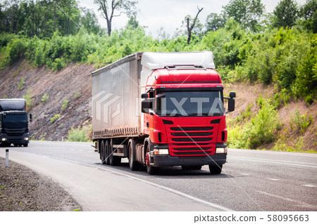 Two trucks moving by a road 58095663