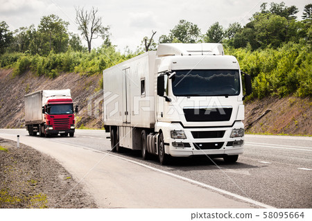 Two trucks moving by a road 58095664