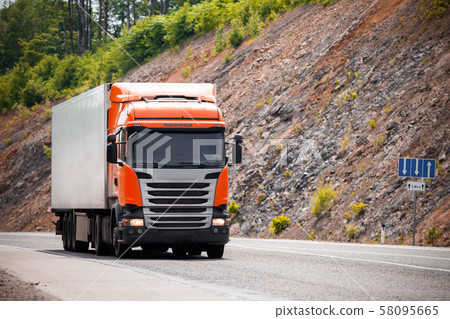 Orange truck moving by a road Orange truck moving by a road 58095665