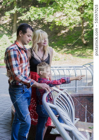 Beautiful happy young family walks in a city park. Beautiful happy young family walks in a city park. 58097028