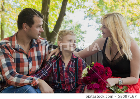 Young family sitting on a bench in a park. 58097167