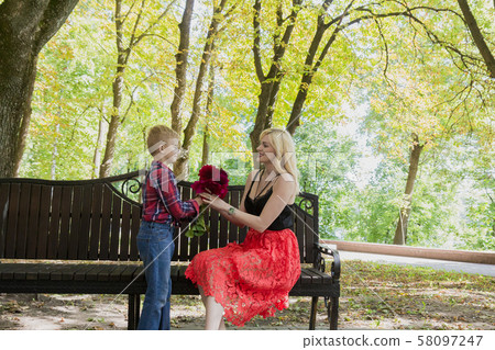 Little beautiful boy gives flowers to mom. Little beautiful boy gives flowers to mom. 58097247