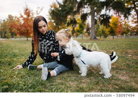 Happy mother and her daughter playing with dog in autumn park. Family, pet, domestic animal and Happy mother and her daughter playing with dog in autumn park. Family, pet, domestic animal and 58097494
