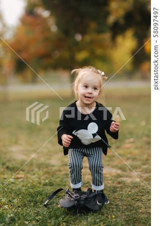 Portrait of little girl walking in the part in autumn. Blond hairl female kid outside. Warm autumn 58097497