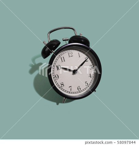 Black classic style alarm clock isolated on green background Black classic style alarm clock isolated on green background 58097844
