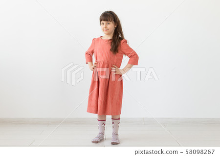 people, kids and fashion concept - little girl posing in clothes at studio. 58098267