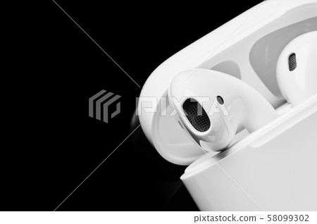 White wireless earphones in case for charging. White wireless earphones in case for charging. 58099302