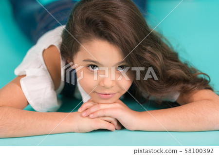 Little child with long brunette hair lie on floor 58100392