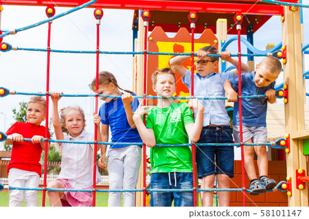 Group of children holding on climbing net Group of children holding on climbing net 58101147