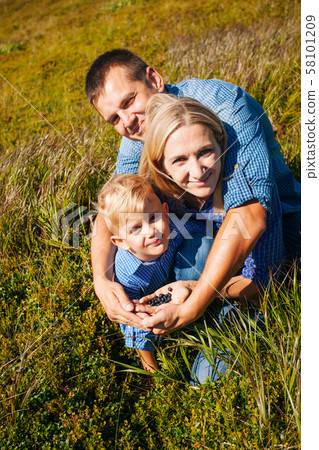 The family tastes wild berries on mountain hills 58101209