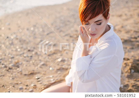 Woman with short hair on beach at sunset Woman with short hair on beach at sunset 58101952