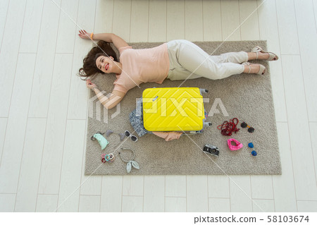 Holidays, voyage and people concept - Young beautiful woman packs a suitcase on a summer travel, top 58103674