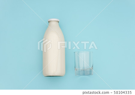 Milk in glass bottle and empty glass on blue Milk in glass bottle and empty glass on blue 58104335