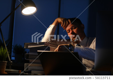 Male businessman sits in office at table sad and looks 58113711
