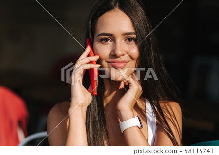 Beautiful brunette female talking on the phone in the cafe. Close ou of woman using phone Beautiful brunette female talking on the phone in the cafe. Close ou of woman using phone 58115741