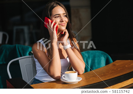 Beautiful brunette female talking on the phone in the cafe. Close ou of woman using phone Beautiful brunette female talking on the phone in the cafe. Close ou of woman using phone 58115742