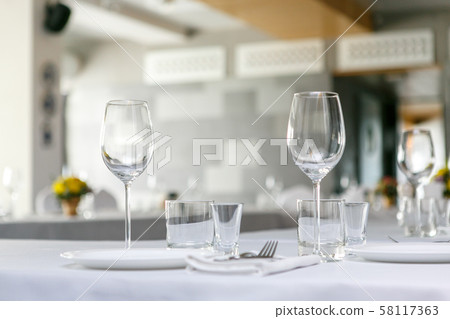 A front view of wine glasses and dishes in the restaurant table set A front view of wine glasses and dishes in the restaurant table set 58117363