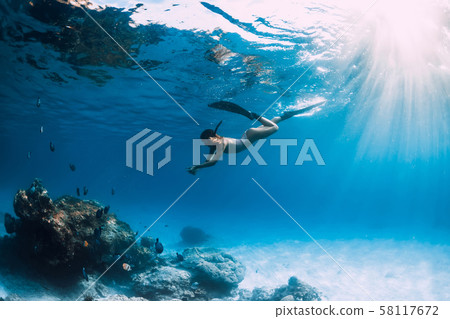 Woman freediver with fins underwater. Freediving and beautiful light in blue ocean 58117672