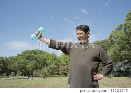Middle-aged men doing muscle training with dumbbells in Yoyogi Park 58121345