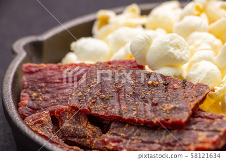 Assorted snacks on skillet. Popcorn and beef jerky. 58121634