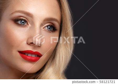 Beautiful blonde in a Hollywood manner with curls, natural makeup and red lips. Beauty face and hair 58121721