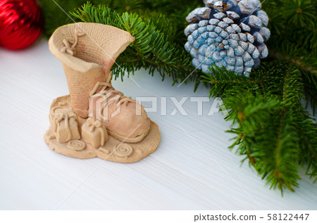 Composition with a decorative boot and New Year's gifts made of clay. Wooden background, decorated 58122447